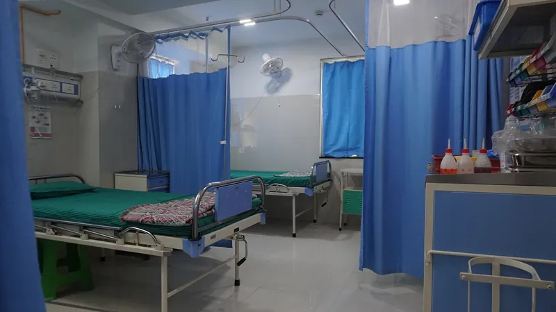 A treatment room at Antara Hospital with beds, blue privacy curtains and a supply trolley.